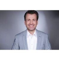 Lars Hachtkemper verstärkt iSi Deutschland als Key Account Manager Professional head-and-shoulders portrait of a smiling man in a light gray blazer and white shirt against a neutral backdrop.